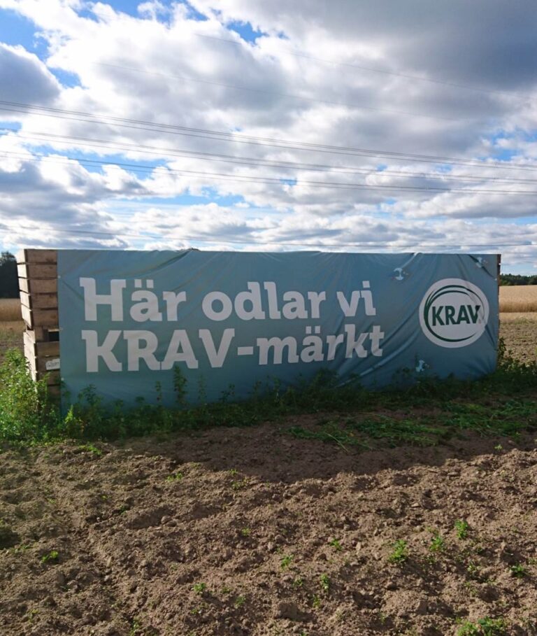 En stor skylt på en åker där det står "Här odlar vi KRAV-märkt"